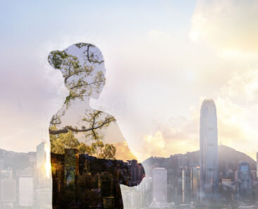 Person standing in contemplation in urban Hong Kong city reflection with nature trees *** Local Caption *** © FangXiaNuo / Getty Images / iStock